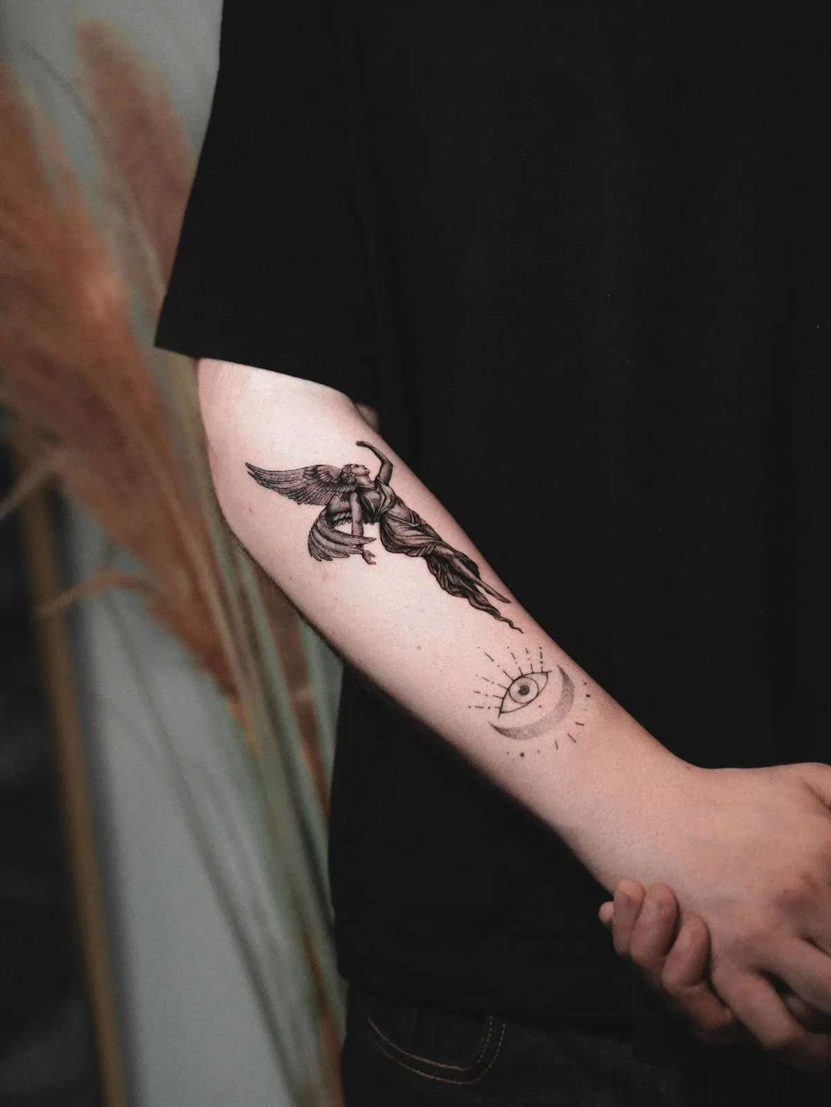 A small winged figure with fine ornaments scattered along a forearm.
