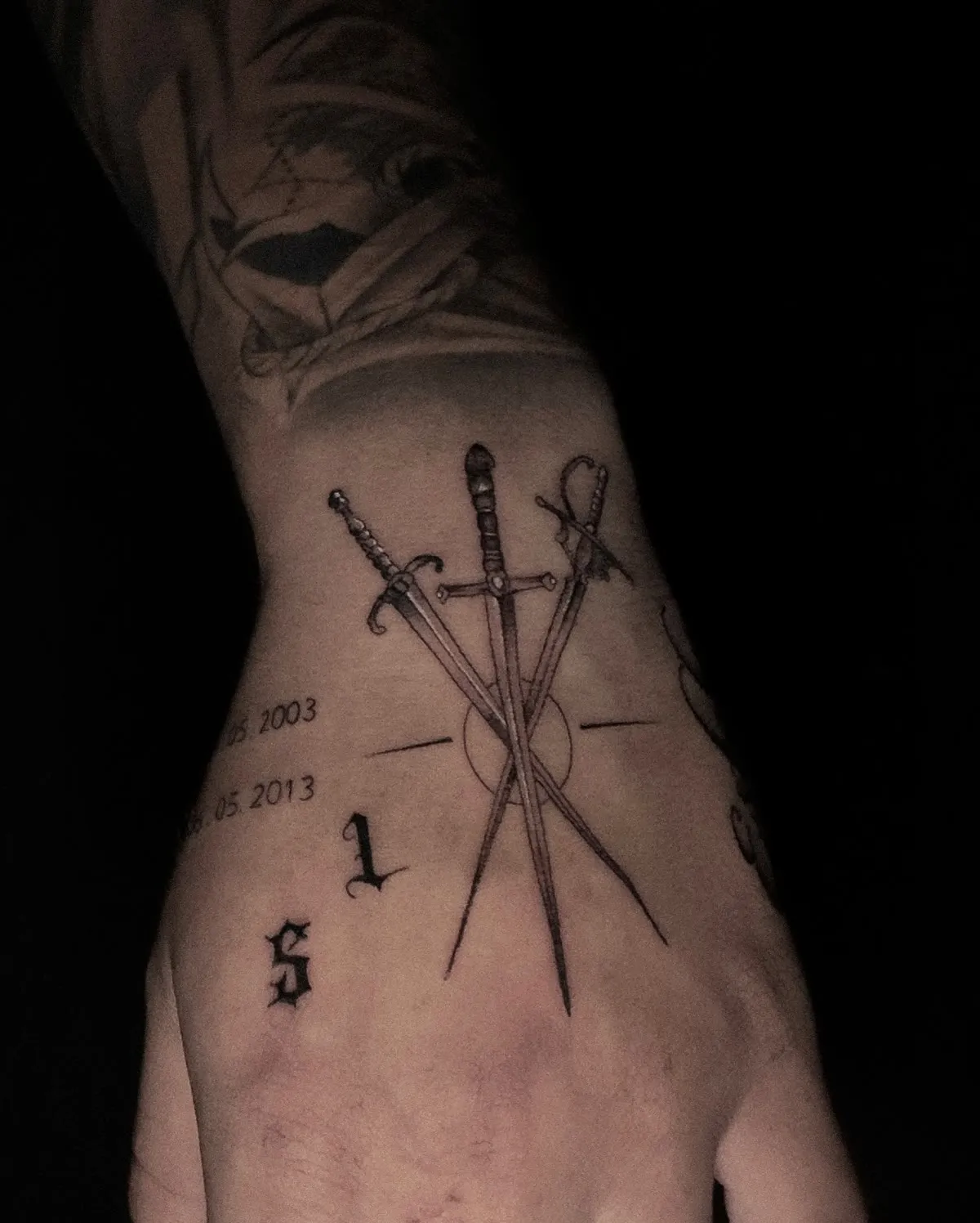 Two crossed swords and small lettering across the back of a hand.