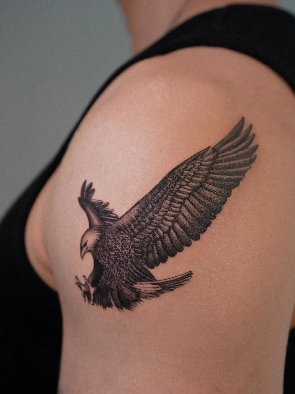 An eagle in flight with its wings spread across a shoulder.
