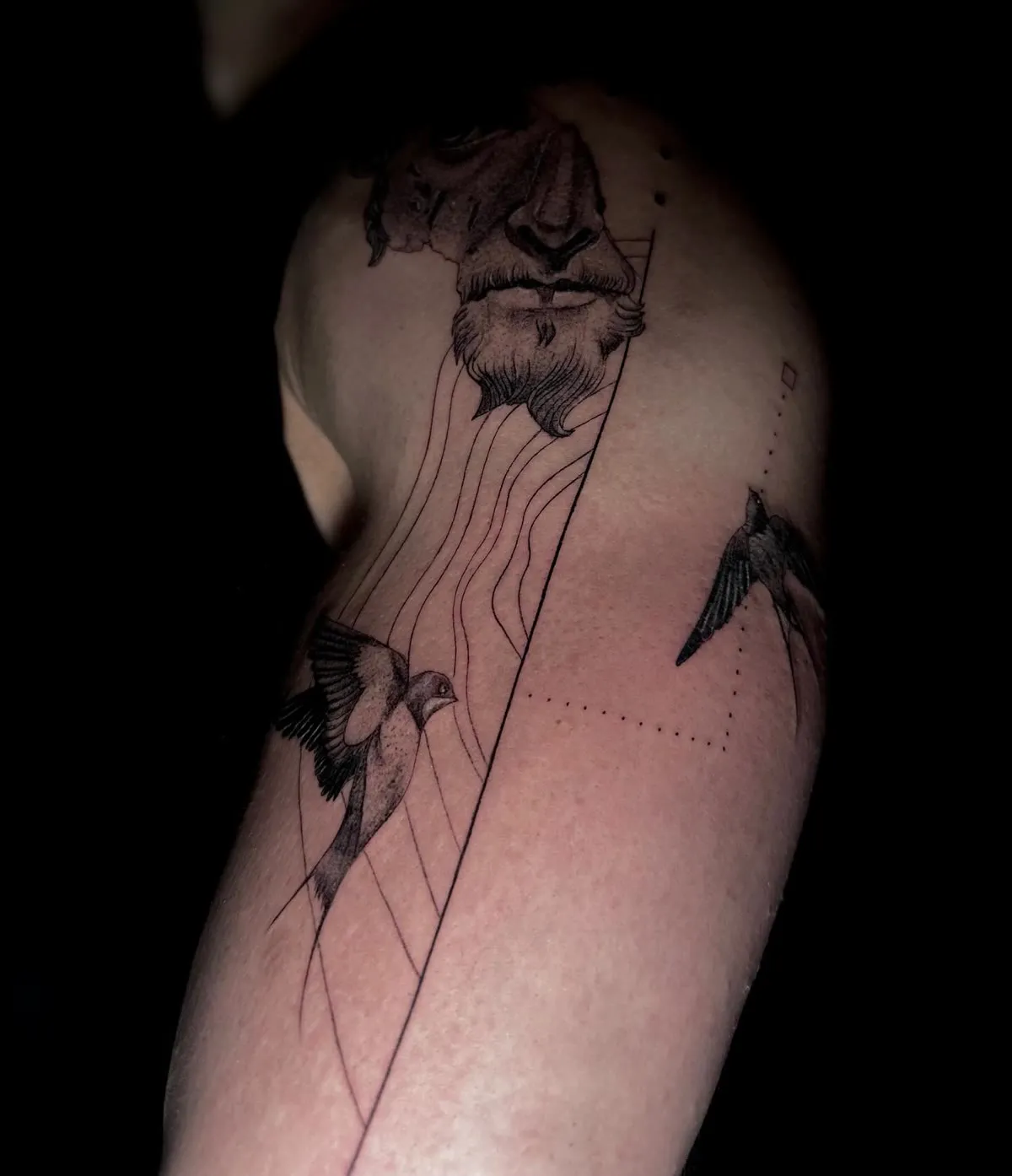 A sleeve in progress: a lion, birds and fine geometric lines down an arm.